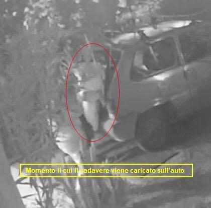 Le telecamere riprendono il momento in cui il cadavere avvolto in un lenzuolo viene carica...