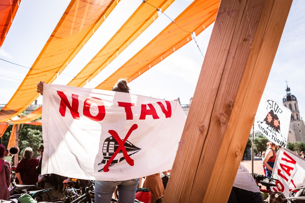Piazza con migliaia di manifestanti, gruppi incappucciati affrontano polizia in tenuta antisommossa tra cantieri di lavoro in montagna
